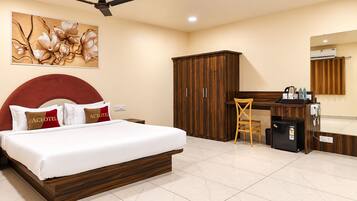 Una habitación de hotel con cama, escritorio, armario y espejo.