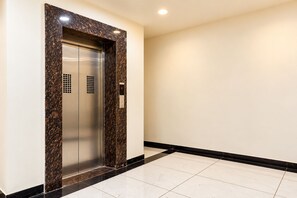 A modern elevator with a marble finish and a digital display. - Aceotel Select Florence, Ujjain (Ujjain)