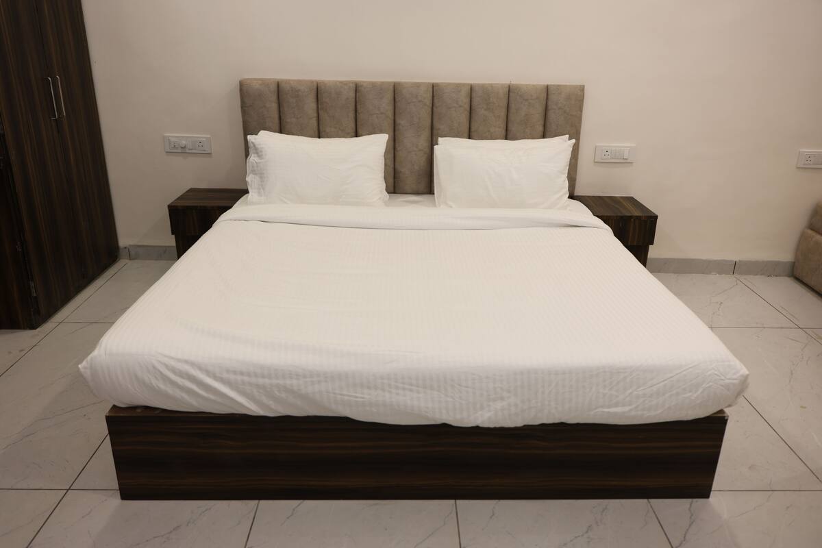 A bed with a wooden frame, two pillows, and a headboard. There are two bedside tables and a wardrobe.