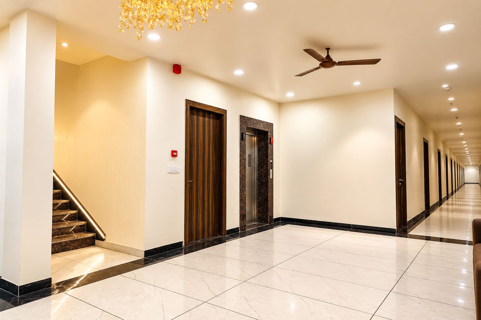 Pasillo de hotel con piso de mármol, puertas de madera y ventilador de techo.