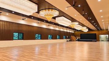 Un hallo espacioso con paneles de madera, varios ventiladores de techo y grandes candelabros.