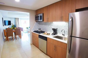 Eine moderne Küche mit Holzausstattung, Edelstahlgeräten, einer gefliesten Spritzschutzwand und einem Essbereich mit Tisch und Stühlen.