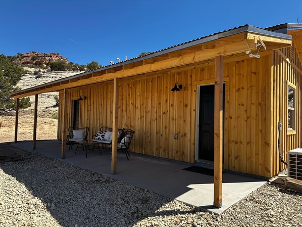 Une cabane en bois dotée d’un patio couvert, de meubles d’extérieur et d’une porte donnant sur l’intérieur.