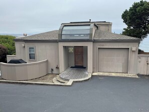 Een modern huis met garage, een overdekte veranda en uitzicht op de oceaan.