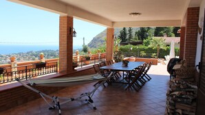 Eine Terrasse mit Tisch und Stühlen, einer Hängematte und Blick auf den Ozean.
