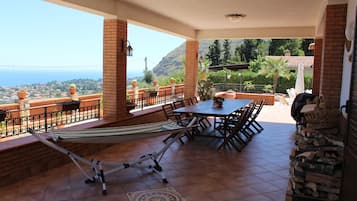 Un patio con tavolo e sedie, un'amaca e vista sull'oceano.