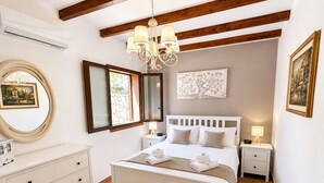 Ein Schlafzimmer mit einem weißen Bett, einem Schminktisch, einer Pendelleuchte, einem Spiegel und Bildern an den Wänden.