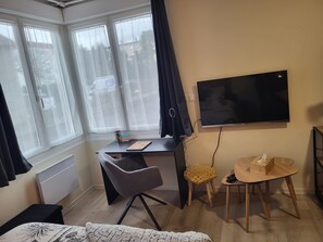 A room with a desk, chair, TV, and a small stool. - Cosy bubble with private terrace and parking area Bed linen and towels provided (Tarbes)