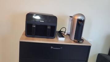 Un meuble noir avec deux tiroirs et une petite machine à café posée sur le dessus.