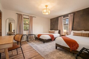 Ein Hotelzimmer mit zwei Betten, einem Holztisch, einem Stuhl, einem Spiegel und einem Fenster mit Vorhängen.