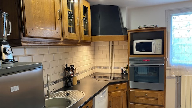 A kitchen with wooden cabinets, a stainless steel refrigerator, a microwave, an oven, and a dishwasher.