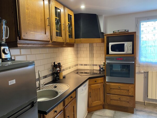 A kitchen with wooden cabinets, a stainless steel refrigerator, a microwave, an oven, and a dishwasher.