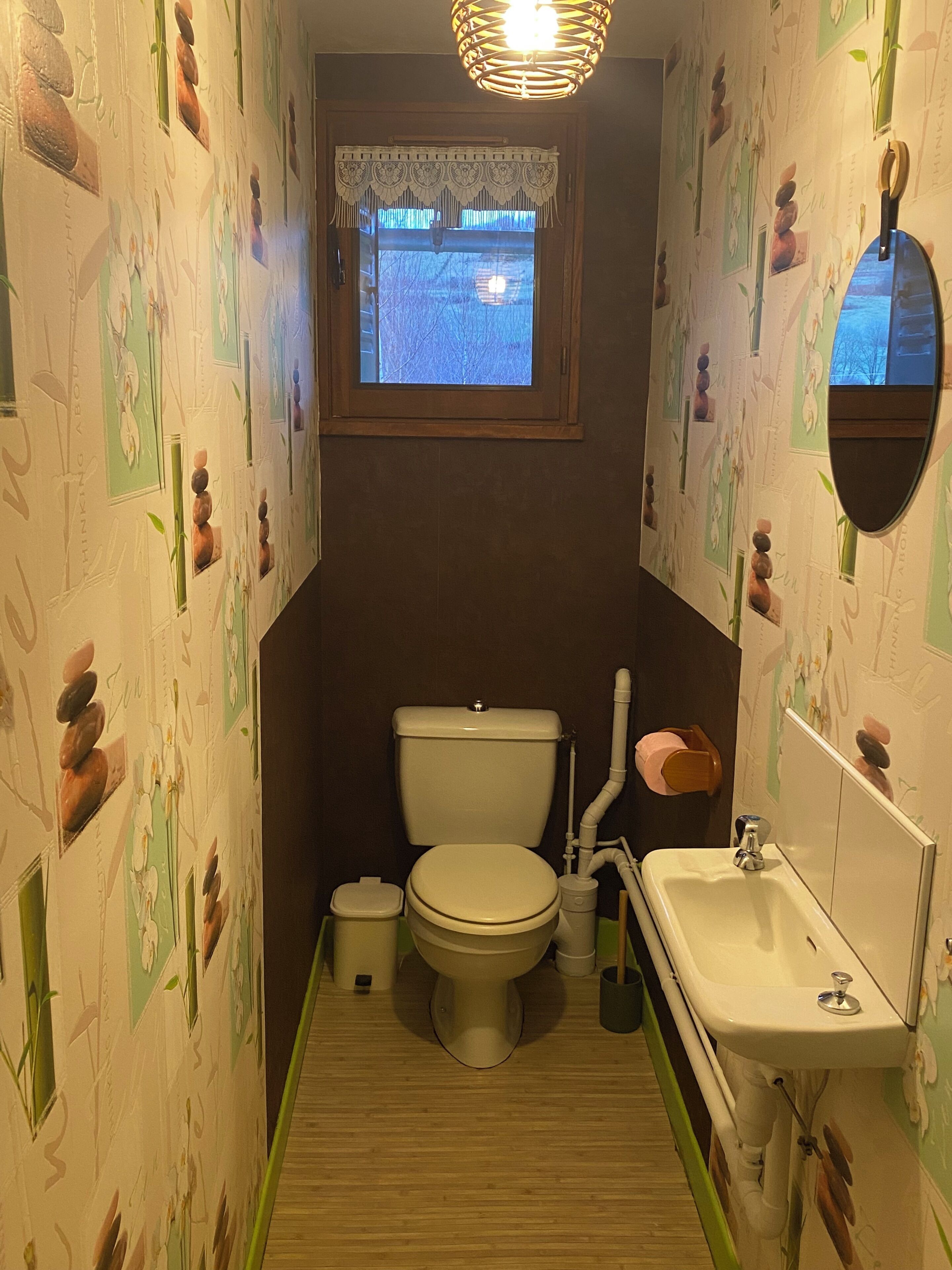 A small bathroom with a toilet, sink, and window.