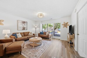 Un salon comprenant un ensemble de canapés, une table basse et un téléviseur posé sur un meuble.