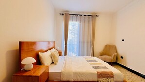Een slaapkamer met een houten bed, een nachtkastje, een stoel en een raam met gordijnen.