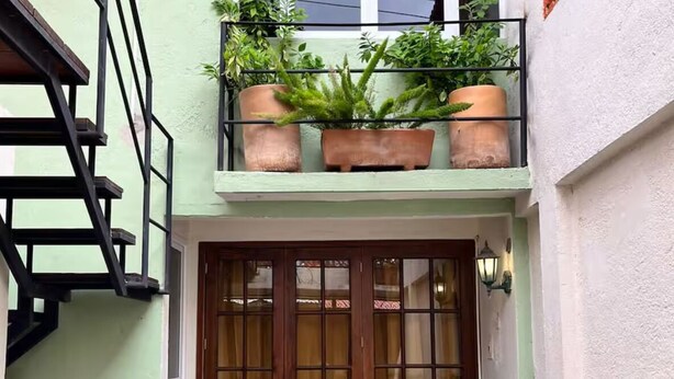 A building entrance with a wooden door, a staircase, and potted plants. - Apartments featuring Oaxaca art for 4 people (Oaxaca de Juárez)