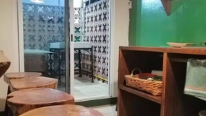 A room with wooden stools, a wooden shelf with baskets, and a view through a glass door to an outdoor area with patterned tiles. - Apartments featuring Oaxaca art for 4 people (Oaxaca de Juárez)