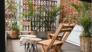 A patio with wooden furniture, including chairs and a table, surrounded by potted plants and a decorative lattice wall. - Apartments featuring Oaxaca art for 4 people (Oaxaca de Juárez)