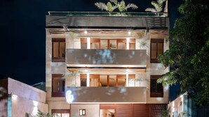 Un edificio moderno de varios pisos con balcones, ventanas amplias y una entrada visible.