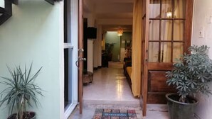 A hallway with a doormat, a potted plant, and a wooden door. - Apartment featuring Oaxacan art for two people, with parking (Oaxaca de Juárez)