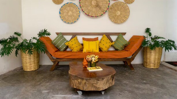 A room with a wooden sofa, two potted plants, a coffee table, and woven wall decorations. - Apartment featuring Oaxacan art for two people, with parking (Oaxaca de Juárez)