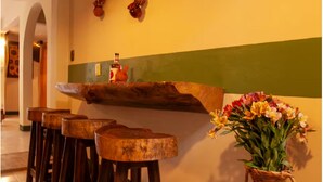 A bar area with stools and a bar counter, a vase of flowers, and a wall with a green stripe. - Apartment featuring Oaxacan art for two people, with parking (Oaxaca de Juárez)