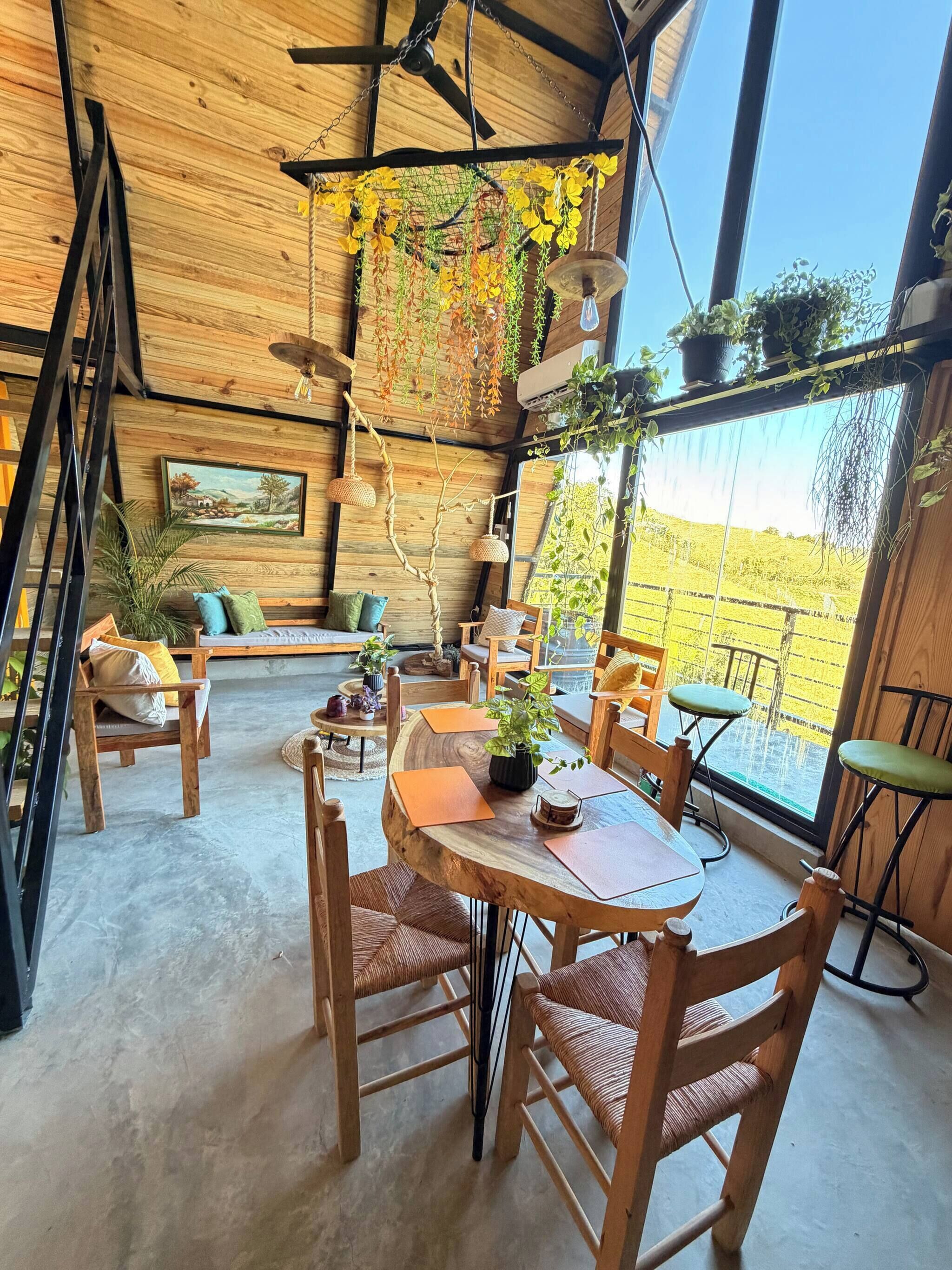 Un intérieur rustique avec un plafond en bois, une table à manger avec des chaises, un canapé et des plantes suspendues.