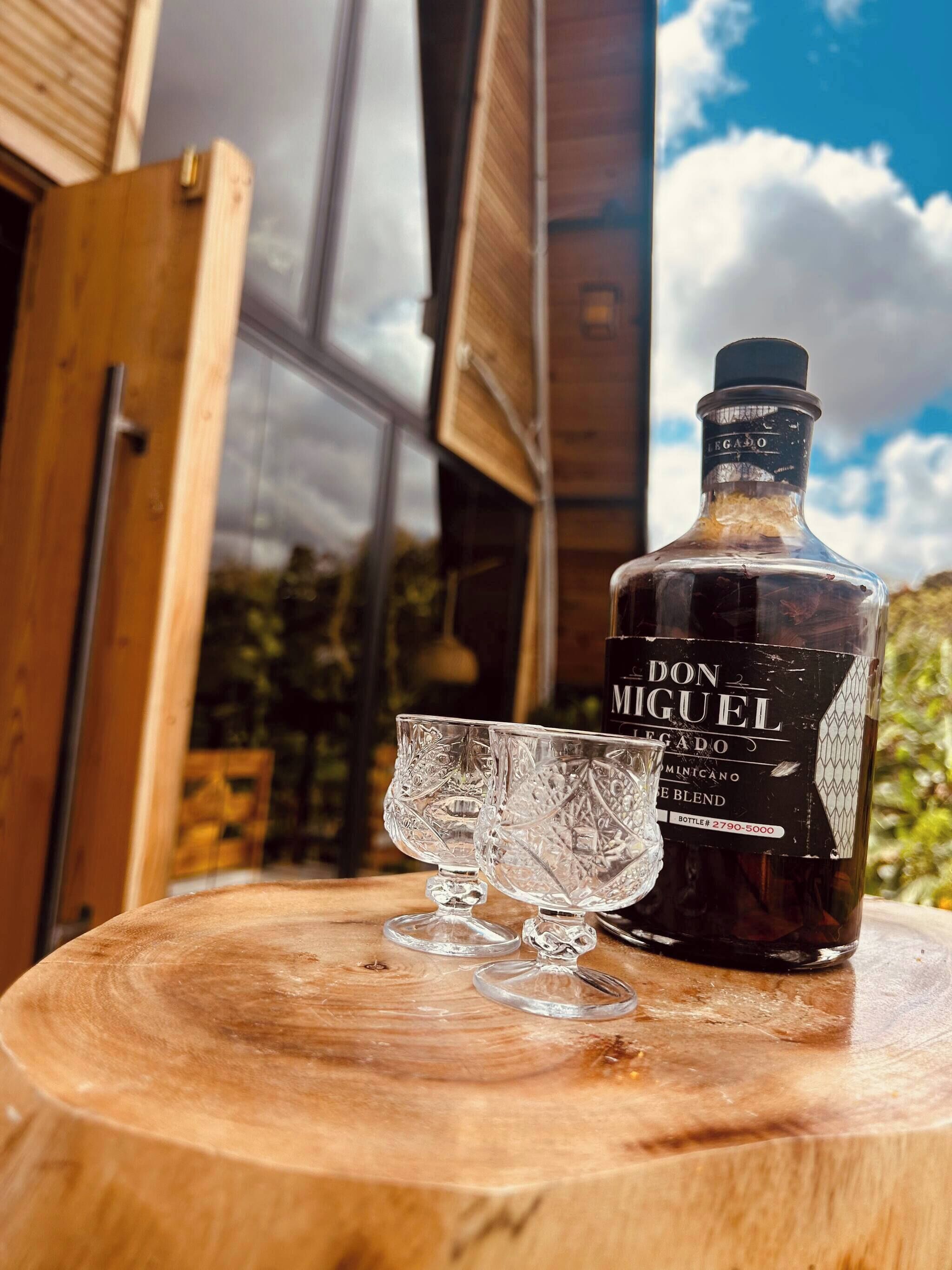 A bottle of Don Miguel legado on a wooden table with two crystal glasses.