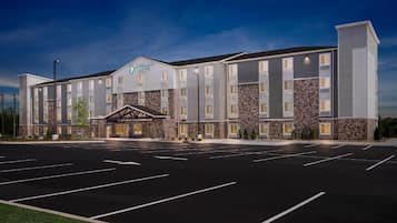 Un grand hôtel moderne, doté d’une façade en pierre, de nombreux étages et d’un vaste parking.
