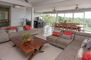 A spacious living room with a large sofa set, a coffee table, and a dining area with chairs and a table. - OUTSTANDING LUXURY, BREATHTAKING VIEWS, 150MB WIFI (Quepos)
