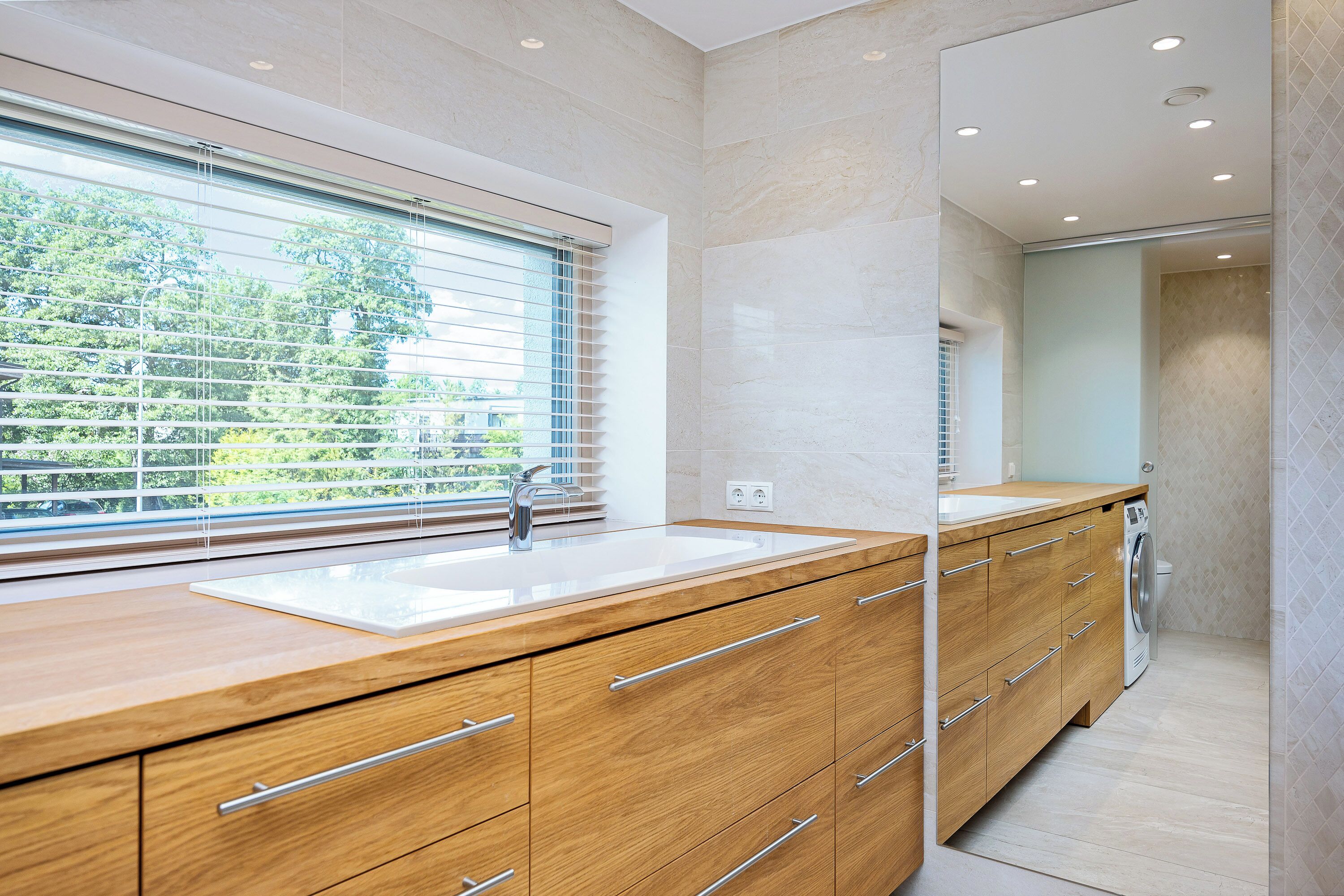A modern bathroom with a wooden vanity, a sink, and a mirror.
