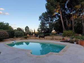 A swimming pool with a stone deck, surrounded by trees and shrubs. - Vrbo Property (Lambesc)