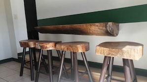 Tres taburetes de madera con patas de metal, un banco de madera y un suelo de baldosas.