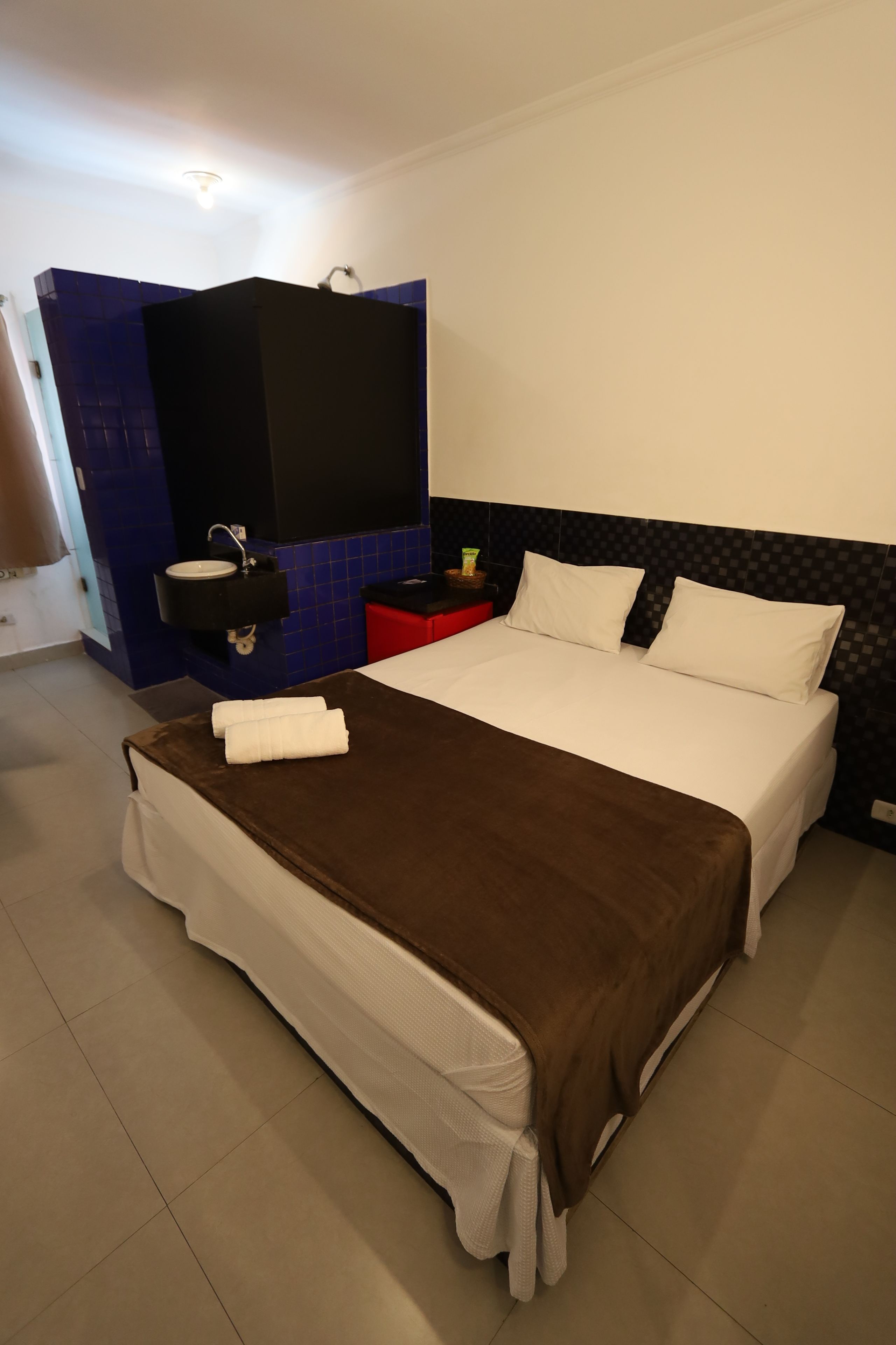 Une chambre d’hôtel avec un lit, une table de chevet, un miroir et un mur bleu.