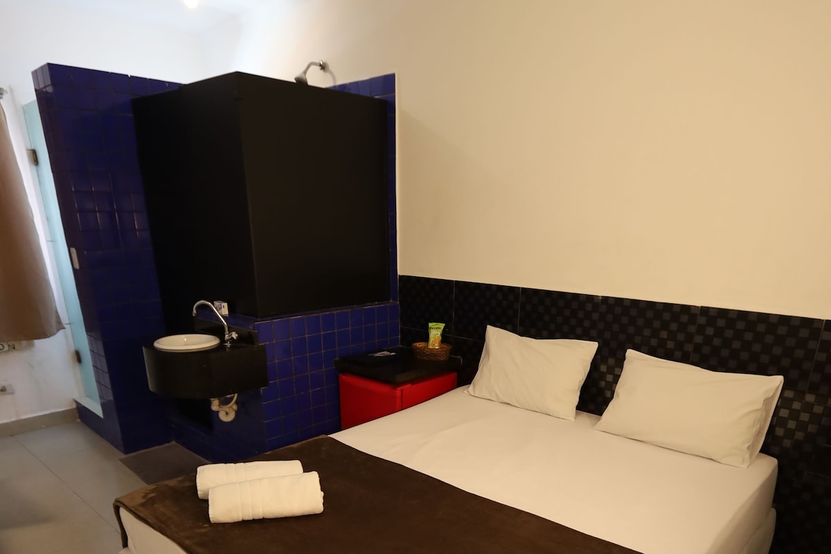 A hotel room with a bed, a nightstand, a mirror, and a blue wall.