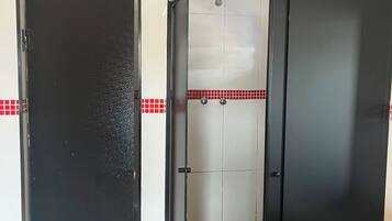 Een kamer met een zwarte deur, een betegelde douchecel en een witte muur met rode tegels.