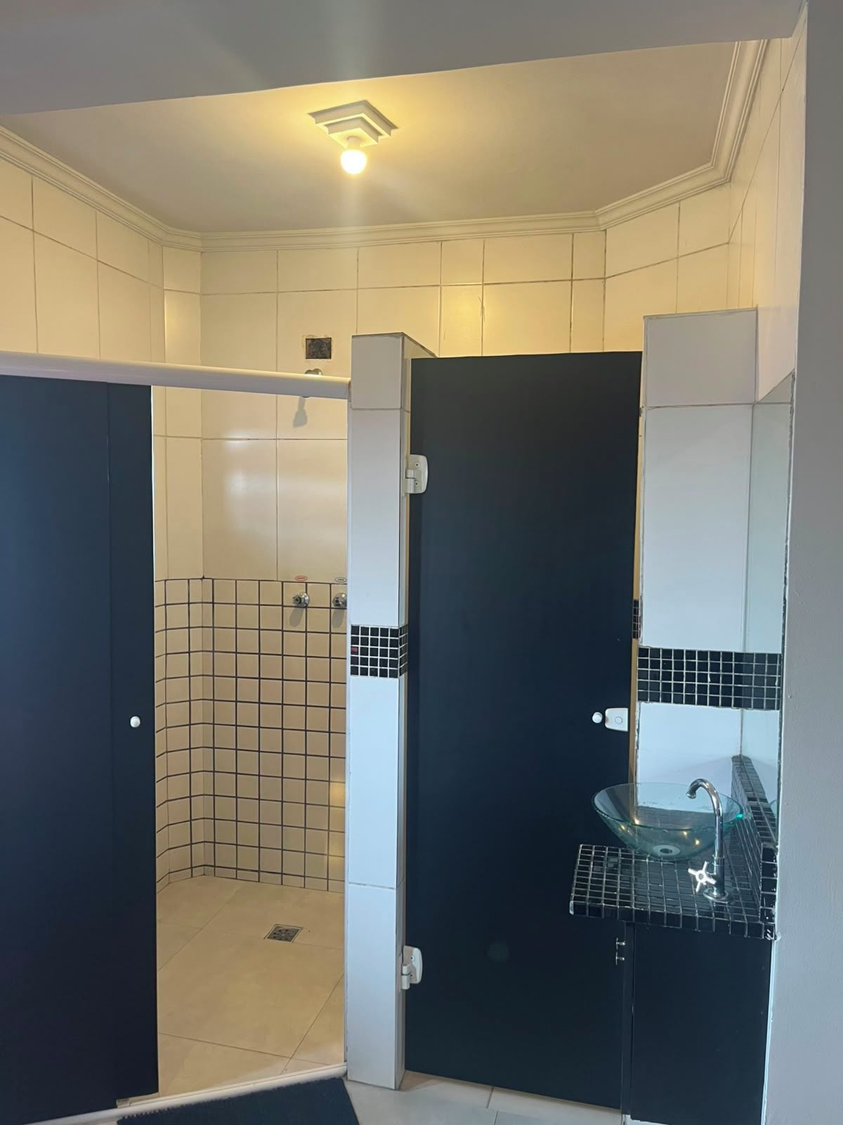 Ein Badezimmer mit Dusche, Waschbecken und einer Tür.