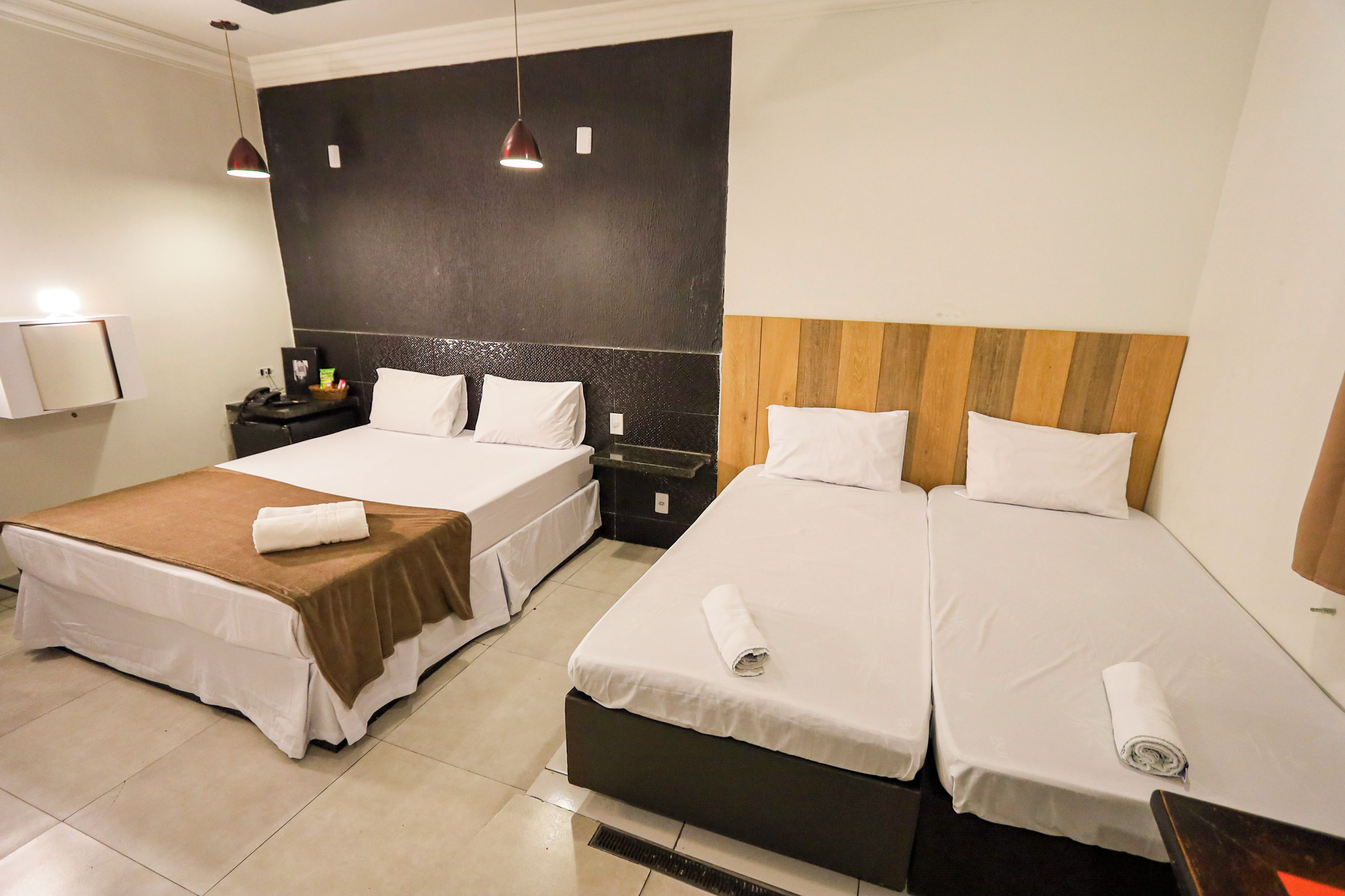 Une chambre d’hôtel avec deux lits, une table de chevet, un téléphone fixé au mur et une serviette sur chaque lit.