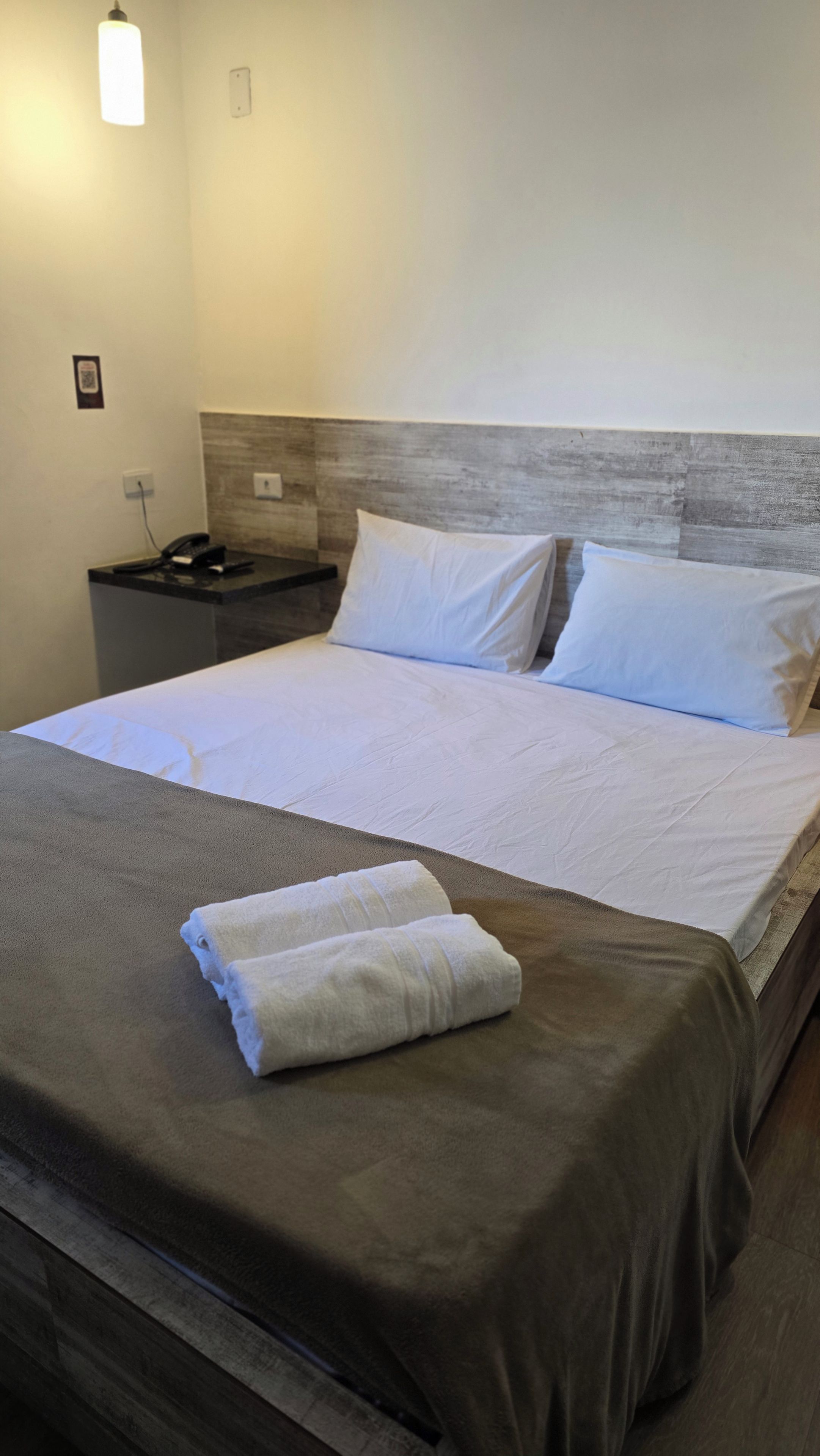 Ein Hotelzimmer mit einem Bett, einem Nachttisch und einem Telefon.