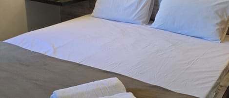 A hotel room with a bed, a nightstand, and a telephone.