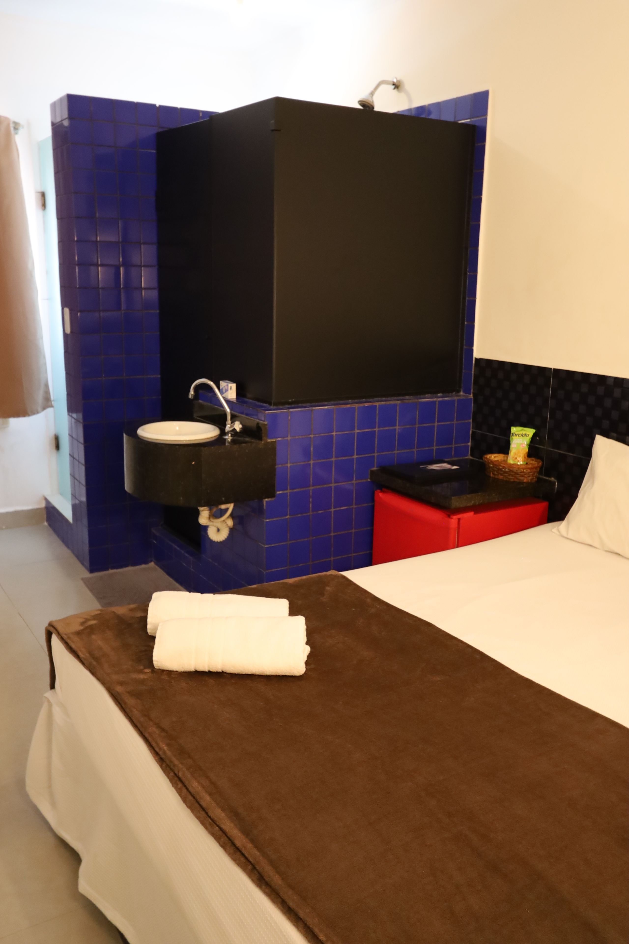 A hotel room with a bed, a bathroom with a sink, and a mirror.