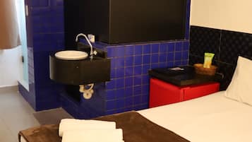 A hotel room with a bed, a bathroom with a sink, and a mirror.