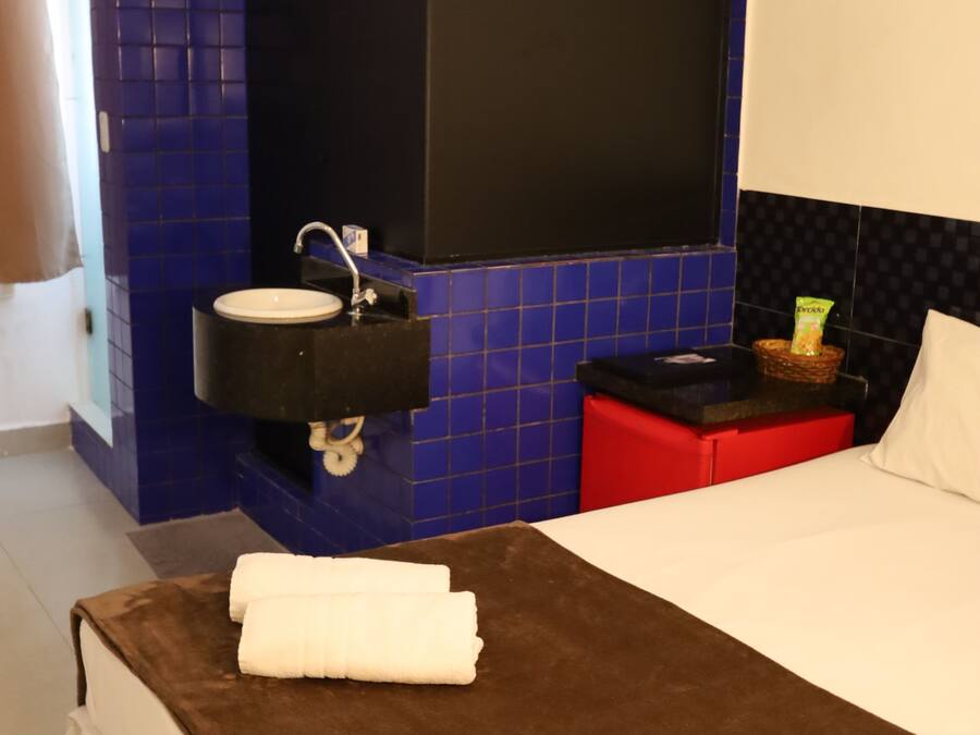 A hotel room with a bed, a bathroom with a sink, and a mirror.