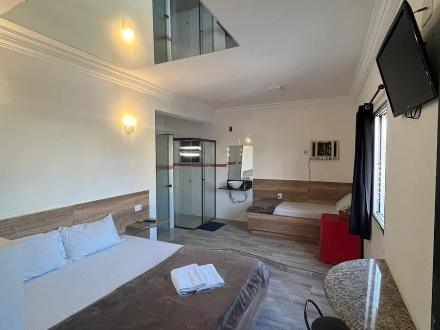 Een hotelkamer met een bed, een bureau, een televisie en een badkamer met douche.