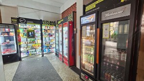 Una tienda de conveniencia con secciones refrigeradas, estantes llenos de aperitivos y un refrigerador de Coca-Cola.