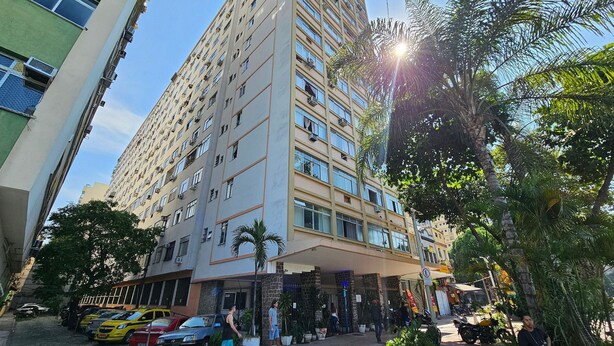 Un edificio de varios pisos con fachada plana, múltiples ventanas y una entrada a nivel de calle con porche cubierto.