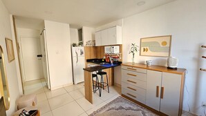 Una cocina compacta con microondas, lavamanos y taburetes de bar.