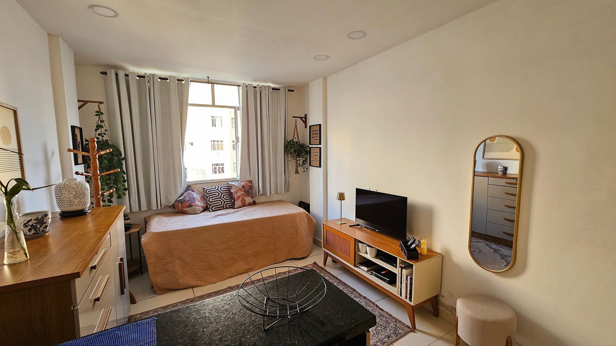 A bedroom with a bed, a TV, a dresser, and a mirror.