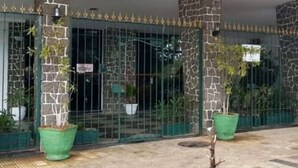 Un edificio con pilares de piedra, una reja de metal y plantas en macetas.