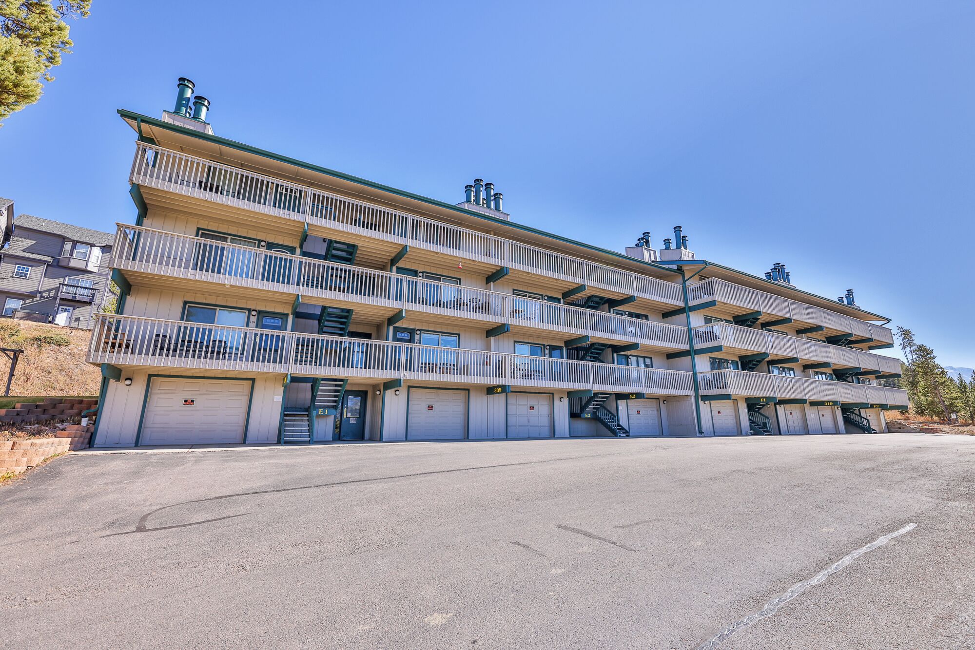 Un immeuble à plusieurs étages doté de balcons, d’un parking et surplombant un ciel dégagé.